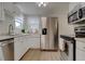 Well-lit kitchen featuring stainless steel appliances, ample counter space, and white cabinets at 1275 S Wolff St, Denver, CO 80219