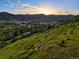 Scenic aerial view of Golden, Colorado, featuring lush green hills and a vibrant sunset over the city at 409 Lookout View Dr, Golden, CO 80401