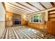 Cozy living room with wood-paneled walls, stone fireplace, beamed ceiling, and large windows at 409 Lookout View Dr, Golden, CO 80401