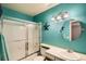 Colorful bathroom featuring turquoise walls, a shower-tub combo, vanity, and decorative accents at 12013 W 56Th Cir, Arvada, CO 80002