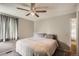 A quaint bedroom with a ceiling fan, a queen-size bed, and a window with curtains at 12013 W 56Th Cir, Arvada, CO 80002