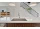 Modern kitchen island featuring a stainless steel sink and faucet with an open view of the staircase at 1231 Newton St, Denver, CO 80204