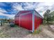 Exterior view of a red barn with white trim and horse in adjacent fenced area at 36921 Ruger Ct, Elizabeth, CO 80107