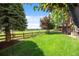 Expansive backyard with a well-maintained lawn, mature trees, and a wooden fence at 12000 Pine Top St, Parker, CO 80138