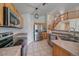 Bright kitchen features stainless appliances, cooktop, tile floors, and adjacent staircase at 10723 W 54Th Pl, Arvada, CO 80002