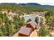 Aerial view of log home nestled near a scenic pond surrounded by lush forest and rolling hills at 9868 Overlook Rd, Sedalia, CO 80135