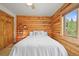 Charming bedroom featuring log walls, a plush white bedspread, and a view of the outdoors at 9868 Overlook Rd, Sedalia, CO 80135