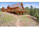 Log cabin with a large deck, stone steps, and wood retaining wall, nestled in a landscaped yard at 9868 Overlook Rd, Sedalia, CO 80135