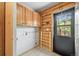Laundry area with log walls, overhead storage cabinets, and a door to the outside at 9868 Overlook Rd, Sedalia, CO 80135