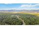 Gorgeous aerial view of a neighborhood with mature trees and a paved road amid distant mountains at 1653 Gore Dr, Larkspur, CO 80118