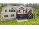 Spacious tan home with a large wooden deck and backyard with lush green grass and mature trees at 1653 Gore Dr, Larkspur, CO 80118