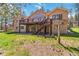 Spacious tan home with a large wooden deck and backyard with lush green grass and mature trees at 1653 Gore Dr, Larkspur, CO 80118