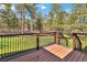 An exterior deck overlooking a backyard with grass and tall pine trees on a sunny day at 1653 Gore Dr, Larkspur, CO 80118