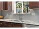 Close-up of kitchen showcasing granite countertops, stainless steel sink, and stylish tiled backsplash at 7092 E Mexico Ave, Denver, CO 80224