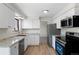 Modern kitchen with white cabinets, stainless steel appliances, light countertops, and durable wood flooring at 6823 Coors St, Arvada, CO 80004
