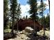 Rustic home nestled among tall trees and large boulders, featuring a two-car garage and a deck at 250 Upper Forest Rd, Idaho Springs, CO 80452