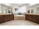 Bright bathroom featuring double sinks, a large soaking tub, neutral tile, and abundant natural light at 23600 E Swallow Cir, Aurora, CO 80016