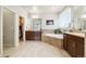 Bright bathroom featuring double sinks, a large soaking tub, neutral tile, and a walk-in closet at 23600 E Swallow Cir, Aurora, CO 80016