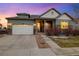 Charming home with a two-car garage, stone accents, and a manicured front yard at dusk at 23600 E Swallow Cir, Aurora, CO 80016