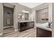 Modern bathroom with double vanity, wood-look tile, and a soaking tub at 14845 Haley Ave, Parker, CO 80134