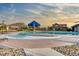 Community pool surrounded by concrete and rocks with a splash umbrella and lounge chairs at 14845 Haley Ave, Parker, CO 80134