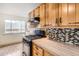 Well-lit kitchen showcases wooden cabinetry, modern appliances, and mosaic-tiled backsplash at 2710 Zenobia St, Denver, CO 80212