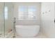 Bright bathroom featuring a soaking tub, glass shower, and shuttered window at 11989 E Lake Cir, Greenwood Village, CO 80111