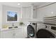 Bright laundry room with stainless steel washer/dryer, white cabinets, and a convenient sink under the window at 11989 E Lake Cir, Greenwood Village, CO 80111