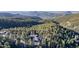 An aerial view of a modern home surrounded by lush forest and rolling hills at 13415 S Resort Dr, Conifer, CO 80433
