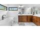 Modern bathroom featuring a soaking tub, sleek wood cabinets, and marble flooring with a view at 13415 S Resort Dr, Conifer, CO 80433