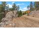 Scenic view of a dirt road winding through a mountain landscape with fall foliage at 13415 S Resort Dr, Conifer, CO 80433