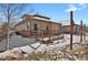 Exterior view showcasing a wood patio, stairs, snow-covered yard, and the home's architectural style at 247 N Coolidge Way, Aurora, CO 80018