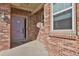 Close up of a brick home's entryway with a lavender door, side window, and classic outdoor lighting at 247 N Coolidge Way, Aurora, CO 80018