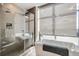 Modern bathroom featuring a glass-enclosed shower, soaking tub, and large window with natural light at 4200 W 17Th Ave # 1013, Denver, CO 80204