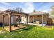 A backyard with a well-maintained lawn, a wooden pergola with a fire pit and comfortable outdoor seating at 10500 Marion St, Northglenn, CO 80233