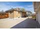 Exterior shot of the house showcasing a brick facade, covered patio, fenced yard, and concrete parking area at 10500 Marion St, Northglenn, CO 80233