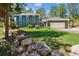 Charming two-story home with manicured lawn, rock features, and lush trees at 7701 Rollins Dr, Larkspur, CO 80118