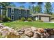Charming two-story home with manicured lawn, rock features, and lush trees at 7701 Rollins Dr, Larkspur, CO 80118