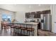 A modern kitchen features an island with bar seating, stainless steel appliances, and an adjacent dining area at 1868 Homestead Dr, Fort Lupton, CO 80621