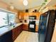 An eat-in kitchen with wood cabinets, black appliances and a large window over the sink at 4996 S Gibraltar Way, Centennial, CO 80015