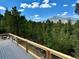 Scenic view from the back deck features a lush forest and distant mountains, ideal for relaxation at 33884 Bergen View Trl, Evergreen, CO 80439