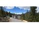 Modern home with mountain views, surrounded by lush trees and a gravel driveway at 33884 Bergen View Trl, Evergreen, CO 80439