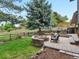 A charming backyard offers a stone patio, a cozy fire pit, a dining area, and green grass for outdoor enjoyment at 7055 E Heritage S Pl, Centennial, CO 80111