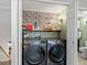 Efficient laundry room with modern washer and dryer, storage shelf, and stylish accent wall design at 7055 E Heritage S Pl, Centennial, CO 80111