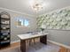 Bright home office with a large desk and a tropical wallpaper accent wall at 7055 E Heritage S Pl, Centennial, CO 80111
