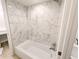 Bathroom featuring a marble-look tiled shower and white bathtub at 14006 E Stanford Cir # K08, Aurora, CO 80015