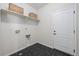 Modern laundry room with dark tile flooring, white walls, and built-in shelves at 42338 Forest Oaks Dr, Elizabeth, CO 80107