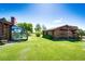Log home boasts a large, well-maintained lawn featuring a greenhouse and shed at 2965 Wagner St, Strasburg, CO 80136