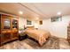 Basement bedroom featuring warm lighting, wood-look flooring, and a comfortable bed with a decorative storage cabinet at 2965 Wagner St, Strasburg, CO 80136