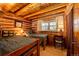 Charming bedroom with twin beds, log walls, warm lighting, and a wooden desk offers a cozy, rustic retreat at 2965 Wagner St, Strasburg, CO 80136